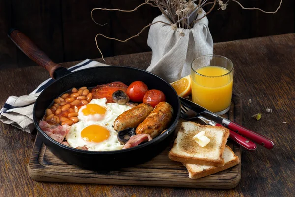 Полный английский завтрак с апельсиновым соком на деревянном столе — стоковое фото