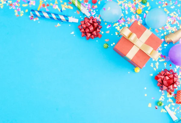 Rode gift box verschillende partij confetti, ballonnen, op blauwe pagina — Stockfoto