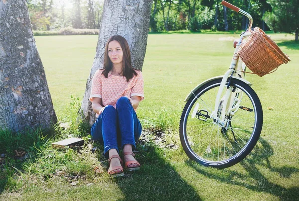 Schöne Frau, die neben einem Baum sitzt — Stockfoto