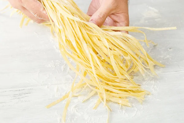 Adam ev yapımı erişte yemek pişiriyor. Ham erişte erkek el ele tutuşur