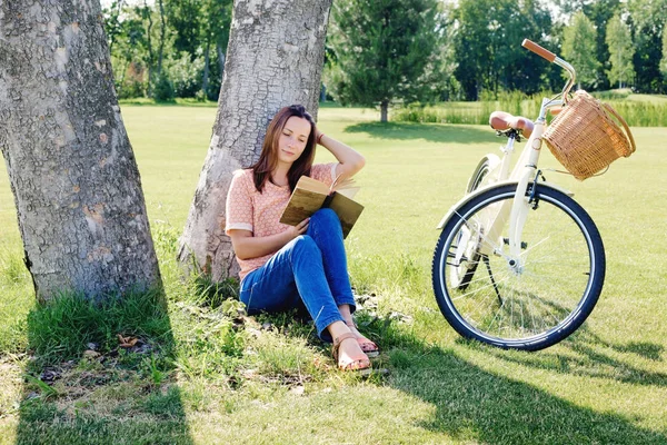 Frau sitzt mit Buch unter Baum — Stockfoto