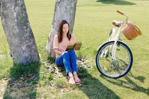 woman sitting under tree with book