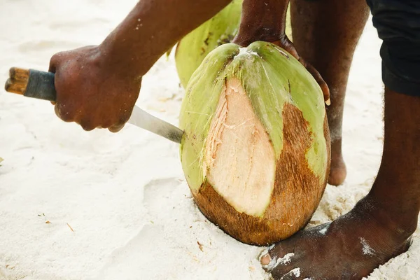 Handen Afrikaanse man Pelt kokosnoot op het strand — Stockfoto