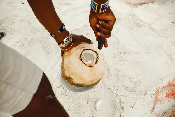 Африканский мужчина чистит кокос на пляже — стоковое фото