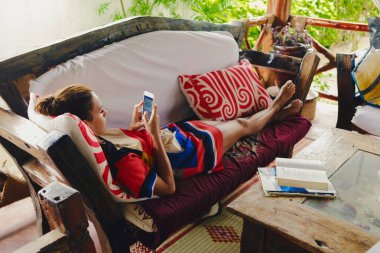 Genç kadın kanepe sundurma içinde yatan sosyal ağlar iletişim kurar.