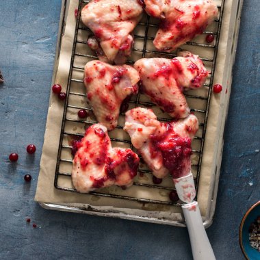 Kara taş yüzeyi kızılcık sosu içinde çiğ tavuk budu