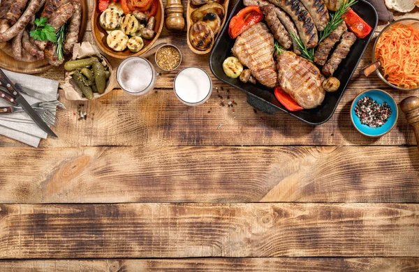 Bife grelhado, salsichas, cerveja e legumes grelhados em madeira — Fotografia de Stock