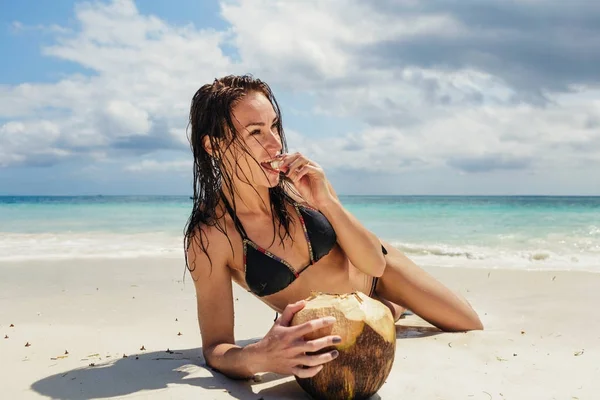 Hermosa mujer en la orilla del océano comiendo coco fresco — Foto de Stock