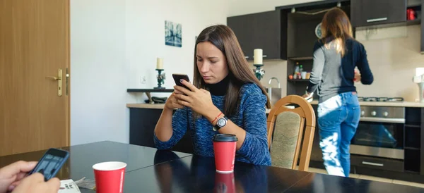 Молода жінка дивиться на смартфон, сидячи вдома — стокове фото