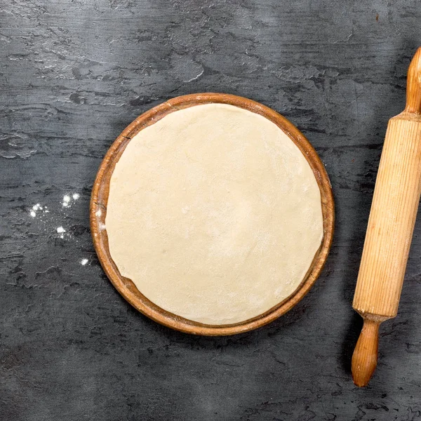 Тесто для пиццы на деревянной доске — стоковое фото