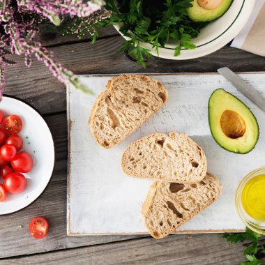 Bruschetta zeytinyağı, kiraz domates ve ahşap masa, üstten görünüm üzerinde avokado ile yemek pişirmek için malzemelerin ayarlayın. İtalyan bruschetta