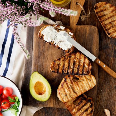 Bruschetta beyaz peynir, domates ve ahşap bir masa, üstten görünüm üzerinde avokado ile yemek pişirmek için maddeler kümesi. Italyan Mutfagi