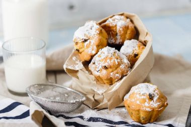 Kuru üzüm ve süt, seçici odak ile çizgili peçete üzerine pudra şekeri ile ev yapımı cupcakes