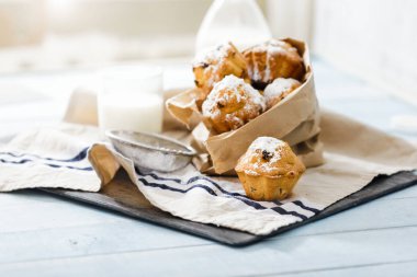 Kuru üzüm ve süt, seçici odak ile mavi ahşap masa üzerine pudra şekeri ile ev yapımı cupcakes