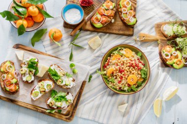 Vejetaryen yemekleri hafif mavi ahşap masa üzerinde. Bruschetta domates, salatalık, Brüksel lahanası ve nohut ve quinoa salata ile ana sayfa görünümü.