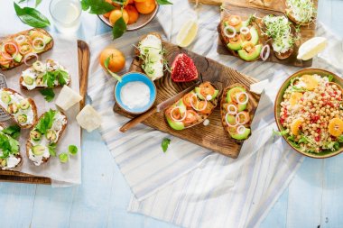 Vejetaryen yemekleri hafif mavi ahşap masa üzerinde. Bruschetta domates, salatalık, Brüksel lahanası ve nohut ve quinoa salata ile ana sayfa görünümü.