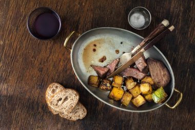 Sığır eti biftek ile kızarmış kabak kızartma tavası kadeh kırmızı şarap ile koyu arka plan üzerinde. Yemek Masası kavramı, üstten görünüm