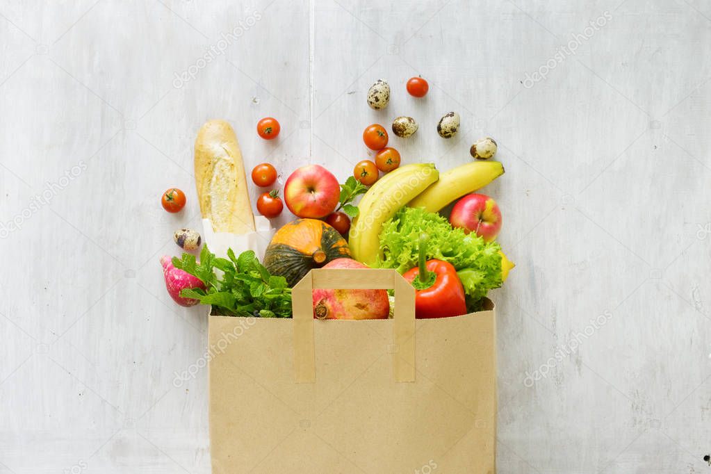 Top view paper bag of different fresh health food on white wooden background. Top view. Flat lay