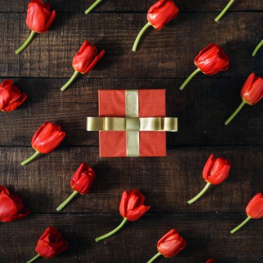 Koyu ahşap arka plan, üstten görünüm üzerinde kırmızı lale ile bir kırmızı hediye kutusu