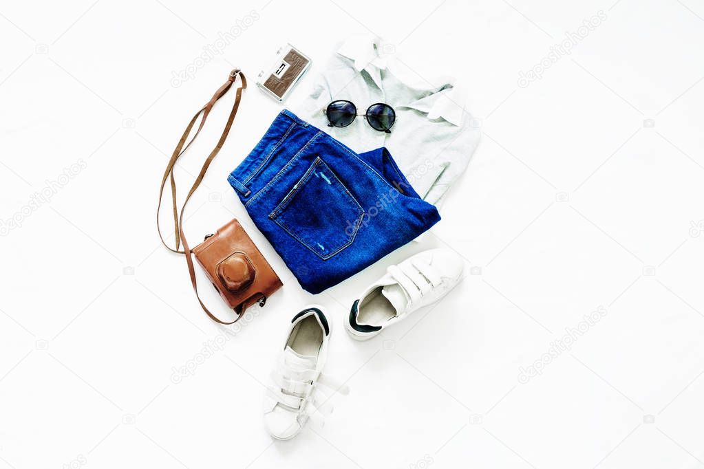 Summer set of female clothes on white background. Female blue jeans, T-shirt, sunglasses and sneakers, top view, flat lay