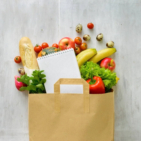 Bolsa de papel de diferentes alimentos saludables y fondo blanco portátil — Foto de Stock