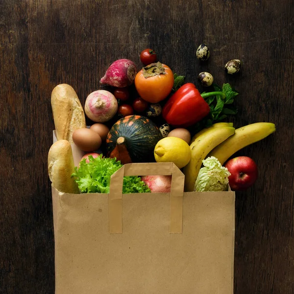 Χάρτινη σακούλα διαφορετικές τροφές υγεία σε σκούρο φόντο ξύλινη — Φωτογραφία Αρχείου