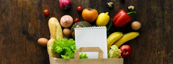 Papiertüte verschiedene Biolebensmittel Notizbuch Holz Hintergrund top v — Stockfoto