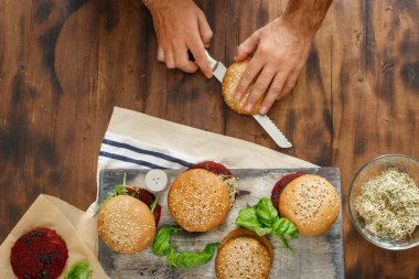 Adam ahşap masa, üstten görünüm üzerinde farklı Topingler vejetaryen Burger hazırlar
