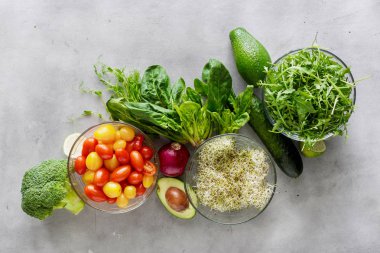 Detoks salata için malzemeler kümesi. Brokoli, ıspanak, avokado, roka, bezelye çekimleri, yonca, soğan, domates ve salatalık gri, en iyi görünüm
