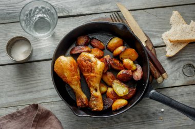 Kızarmış tavuk budu ahşap masa, üstten görünüm üzerinde tavada kızarmış patates ile