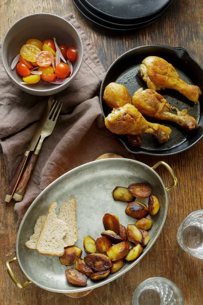 煎鸡腿在煎锅在黑木桌用土豆和沙拉 餐桌概念 — 图库照片