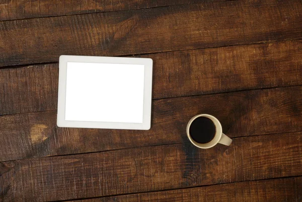 White tablet with cup coffee on dark wooden table, top view