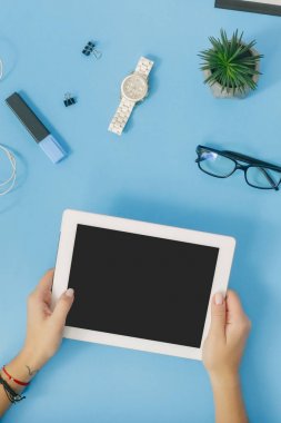 Kadınsı çalışma alanı kavramı, erkek mavi zemin üzerine beyaz tablet tutan eller. Düz yatıyordu, en iyi görünümü