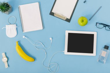 Kadınsı office çalışma alanı kavramı, beyaz tablet ile defter ve Pano ve kulaklık mavi masada meyve 