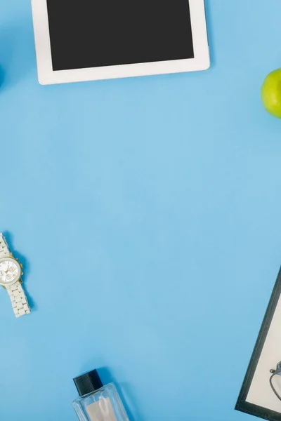 tablet with supplies for education on blue background, top view