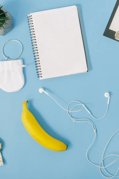 Office Arbetsplatsen Koncept Anteckningsbok Med Banan Och Hörlurar Blå Bakgrund — Stockfoto