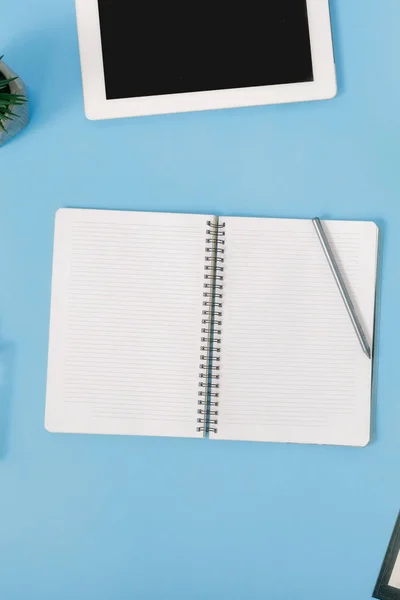Schreibtischarbeitsplatz Mit Geöffnetem Notizbuch Und Tablet Auf Blauem Hintergrund — Stockfoto