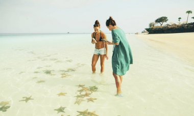 Starfishes okyanus üzerinde güneşli gün dikkate alınarak iki genç kadın gezginler