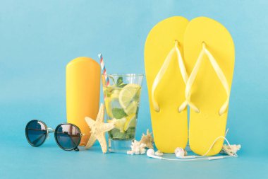 Yaz flip flop ve plaj aksesuarları üzerinde mavi arka plan ile kokteyl serinletici