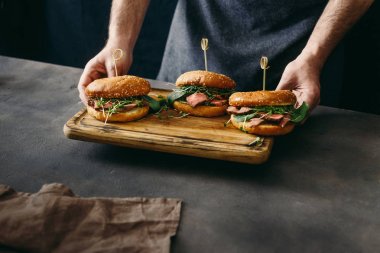 Adam kesme kurulu set burger sığır eti az pişmiş ile tutarak, ıspanak, yeşil sos ve mikro Yeşiller