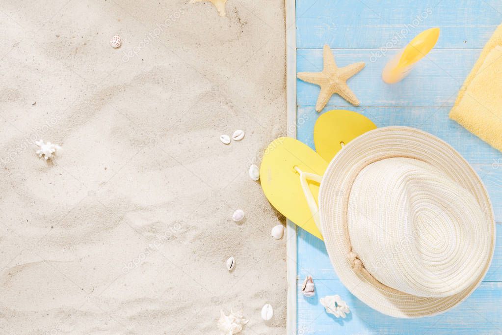 Top view straw hat, flip flops, sunblock, towel, seashells with copy space. Traveler accessories on sand. Travel vacation concept. Summer background