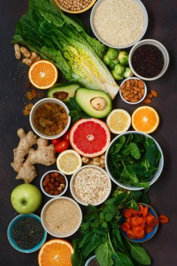 Üstten Görünüm temiz yemek ayarla. Vejetaryen sağlıklı yiyecekler - farklı sebze ve meyve, superfood, tohumlar, tahıl, yaprak sebze koyu arka plan üzerinde. Düz yatıyordu