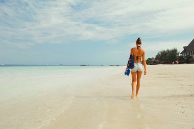 Okyanus kıyı sabahları yürüyüş bir sırt çantası ile geri genç kadından görüntülemek