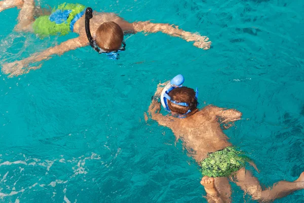 Two children swim in the ocean with snorkeling mask. Summer background