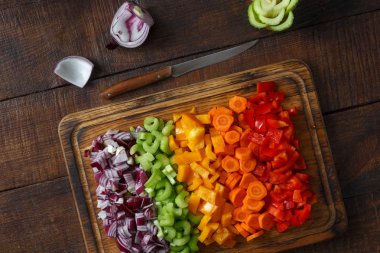 Dilimlenmiş taze sebze kesme tahtası ahşap arka plan üzerinde hizmet veren kümesi.