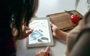 Online alışveriş kavramı. İki genç kadın yaz giysileri online satın eve mutfakta