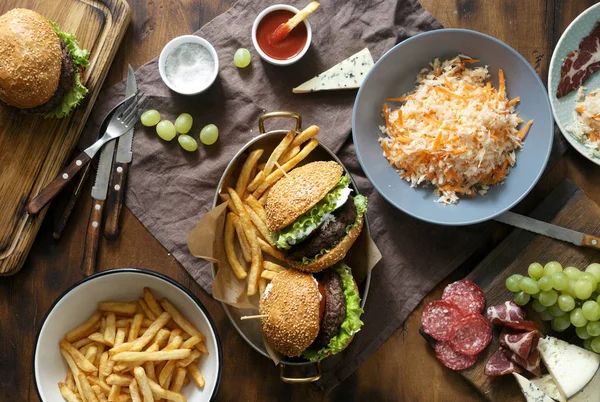 Koncepcja Stołu Hamburgery Frytki Patelni Drewnianym Stole Serwowane Sosem Sałatki — Zdjęcie stockowe