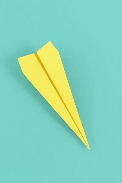 パステル調の青の背景にフラット横たわっていた黄色の紙飛行機 — ストック写真