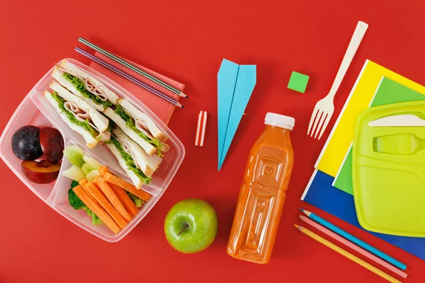 赤の背景にヘルシーなランチ ボックスとサンドイッチ 新鮮な野菜 ジュース 学校のボトル供給します — ストック写真