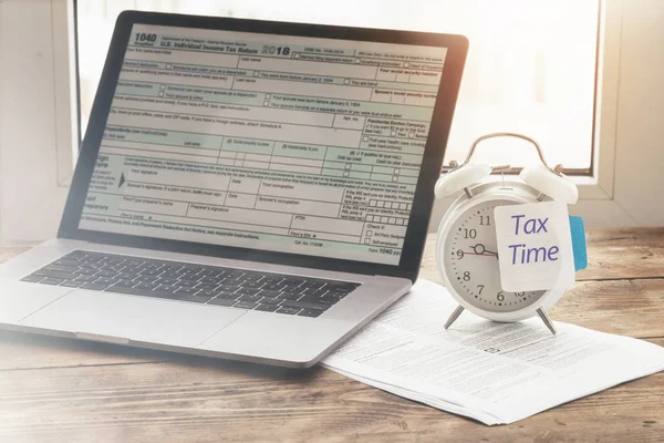 Alarm clock with note tax time. Reminder of the need to file tax returns, tax form